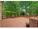 Large wooden deck surrounded by trees, with a wooden railing, brick pillars, and potted plants at 1100 Kensington Ct, Johns Creek, GA 30022