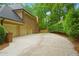Brick home exterior with three-car garage, expansive driveway, and well-maintained landscaping at 1100 Kensington Ct, Johns Creek, GA 30022
