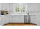 Well-lit kitchen features white cabinetry, stainless steel appliances, and hardwood floors at 1100 Kensington Ct, Johns Creek, GA 30022