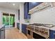 Modern kitchen featuring stainless steel appliances, blue cabinets, and access to the outdoor living space at 340 Colewood Way, Atlanta, GA 30328
