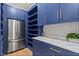 Well-organized pantry with custom shelving, stainless steel refrigerator, and ample storage with blue cabinetry at 340 Colewood Way, Atlanta, GA 30328