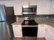 Modern kitchen with stainless steel appliances, white cabinets, and tile backsplash at 3948 Valley Brook Rd, Snellville, GA 30039