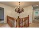 Upper landing with wood railing, chandelier, and access to rooms at 5621 Wildwood Trl, Lithonia, GA 30038