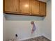 Clean laundry area with tile flooring, overhead cabinets, and red and blue connections for a washer and dryer at 5621 Wildwood Trl, Lithonia, GA 30038