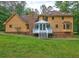 Back of house featuring outdoor deck, brick chimney, and lush green yard at 5621 Wildwood Trl, Lithonia, GA 30038