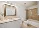 Bathroom featuring a tile-surrounded bathtub with glass enclosure and a white vanity with large mirror at 20 10Th Nw St # 2003, Atlanta, GA 30309