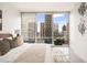 A modern bedroom offers city views from its large window and minimalist decor at 20 10Th Nw St # 2003, Atlanta, GA 30309
