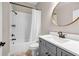 Bathroom with tiled shower, vanity with gray cabinets, and round mirror at 6351 Granbury Nw Walk, Acworth, GA 30101