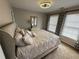 A bedroom with neutral walls and carpet features a bed, a light fixture, and two windows at 2122 Riverbirch Ct, Lawrenceville, GA 30044