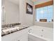 Bathroom features a tub, window, neutral wall color, and attractive granite countertop on the vanity at 420 Bear Cub Path, Social Circle, GA 30025