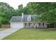 Inviting home featuring a covered porch, attached garage, and lush green yard at 420 Bear Cub Path, Social Circle, GA 30025