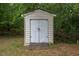 A sturdy, simple shed with double doors offers great storage space in a wooded backyard setting at 420 Bear Cub Path, Social Circle, GA 30025