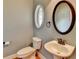 Powder room with oval window, round mirror, and pedestal sink with bronze faucet at 5195 Stefan Ridge Way, Buford, GA 30519