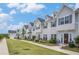 Row of new townhomes with gray siding, red doors, green lawns, and sidewalks under a blue sky at 1702 Prospect Way, Conyers, GA 30094