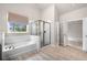 Bright bathroom showcases a soaking tub and glass shower framed by subway tiles and a neutral color pallette at 8230 Dawson View Way, Cumming, GA 30028