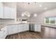 White kitchen boasts stainless appliances, stone counters, and modern lighting at 8230 Dawson View Way, Cumming, GA 30028