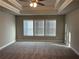Expansive main bedroom featuring tray ceilings, plush carpeting, and three windows with blinds at 2458 Morgan Creek Rd, Buford, GA 30519