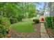 Lush backyard with a manicured lawn, mature trees, and a cozy patio with red chairs at 2773 Brookgrove Se Ln, Atlanta, GA 30339