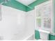 Modern bathroom featuring a tub with white tile surround, shower head, and window with white shutters at 2773 Brookgrove Se Ln, Atlanta, GA 30339