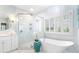 Luxurious bathroom featuring a soaking tub, glass-enclosed shower, and marble tile at 2773 Brookgrove Se Ln, Atlanta, GA 30339