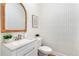 Chic powder room featuring neutral geometric wallpaper, granite countertop, and rattan framed mirror at 2773 Brookgrove Se Ln, Atlanta, GA 30339