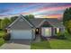 Charming single-story home showcasing a landscaped front yard, bay window, and two-car garage with a beautiful sunset in the background at 2602 Midler Ct, Buford, GA 30519