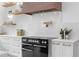 Close up of a kitchen range and pot filler, featuring white cabinetry and countertops with open shelves at 575 Indian Hills Pkwy, Marietta, GA 30068