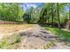 Wide gravel area in the backyard surrounded by trees, offering a versatile space for various activities at 5855 Willis Ln, Cumming, GA 30040