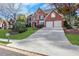 Charming two-story brick home with a well-manicured lawn, mature trees, and a spacious driveway leading to a two-car garage at 1215 Wynridge Xing, Alpharetta, GA 30005