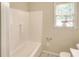 Bathroom highlighting a bathtub with white tile surround, a window and a toilet at 1236 Stone Mountain Lithonia Rd, Lithonia, GA 30058