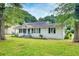 Home exterior featuring a white facade, black shutters, and mature trees at 1236 Stone Mountain Lithonia Rd, Lithonia, GA 30058