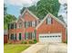 Charming two-story brick home with a well-manicured lawn and a two-car garage in a suburban neighborhood at 1485 Oglethorpe Run Ln, Suwanee, GA 30024