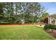 Expansive backyard with a lush lawn, mature trees, and a cozy patio area for outdoor enjoyment at 205 Devon Downs Pl, Alpharetta, GA 30005