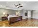 Large bedroom with a trey ceiling, a ceiling fan, hardwood floors, and an accent wall at 205 Devon Downs Pl, Alpharetta, GA 30005
