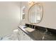 Modern bathroom featuring a black marble countertop and a gold-framed oval mirror at 3006 Skyland Ne Dr, Brookhaven, GA 30319