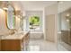 Bright, luxurious bathroom featuring dual sinks, marble countertops, soaking tub, and glass-enclosed shower at 3006 Skyland Ne Dr, Brookhaven, GA 30319