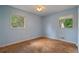 Empty bedroom featuring blue walls, two windows and hardwood floors at 34 Duke Dr, Lawrenceville, GA 30046