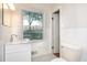 This bathroom is bright with white tile, a white vanity, and a large window overlooking the property at 574 Oak Grove Rd, Temple, GA 30179