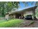 Carport attached to the home with a car parked underneath and overgrown vegetation at 2214 River Rd, Ellenwood, GA 30294