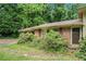 Close up view of the front of the house with overgrown bushes and a yard at 2214 River Rd, Ellenwood, GA 30294
