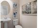 Elegant powder room featuring pedestal sink, oval mirror, toilet, and decorative wall art at 286 Abbotts Crossing Cir, Conyers, GA 30094