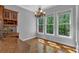 Bright breakfast nook featuring hardwood floors, a modern chandelier, and large windows overlooking a lush, wooded backyard at 5407 Waters Edge Trl, Roswell, GA 30075