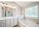 Clean bathroom features a tub, double vanity, and large window for natural light at 1216 Foxcroft Ln, Cumming, GA 30041