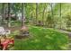 Backyard with a fire pit and chairs surrounded by mature trees and lush greenery at 1880 Barrett Dr, Cumming, GA 30040
