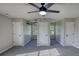 Large bedroom with three doors, two windows, gray carpet, and a ceiling fan at 1700 Conductor Ln, Conyers, GA 30013