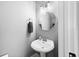 Half bath with pedestal sink, round mirror, and modern lighting at 577 Cypher Dr, Suwanee, GA 30024