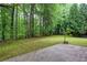 A concrete patio looks out onto a verdant backyard with lush trees in this home's outdoor space at 6939 Waters Edge Dr, Stone Mountain, GA 30087