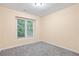 This bedroom features neutral carpet and walls and a bright window with a view of the outdoors at 6939 Waters Edge Dr, Stone Mountain, GA 30087