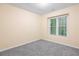 This bedroom features neutral carpet and walls and a bright window with a view of the outdoors at 6939 Waters Edge Dr, Stone Mountain, GA 30087