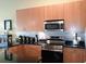 Close up of a modern kitchen with stainless steel appliances, wood cabinets, and black countertops at 711 Cosmopolitan Ne Dr # 123, Atlanta, GA 30324
